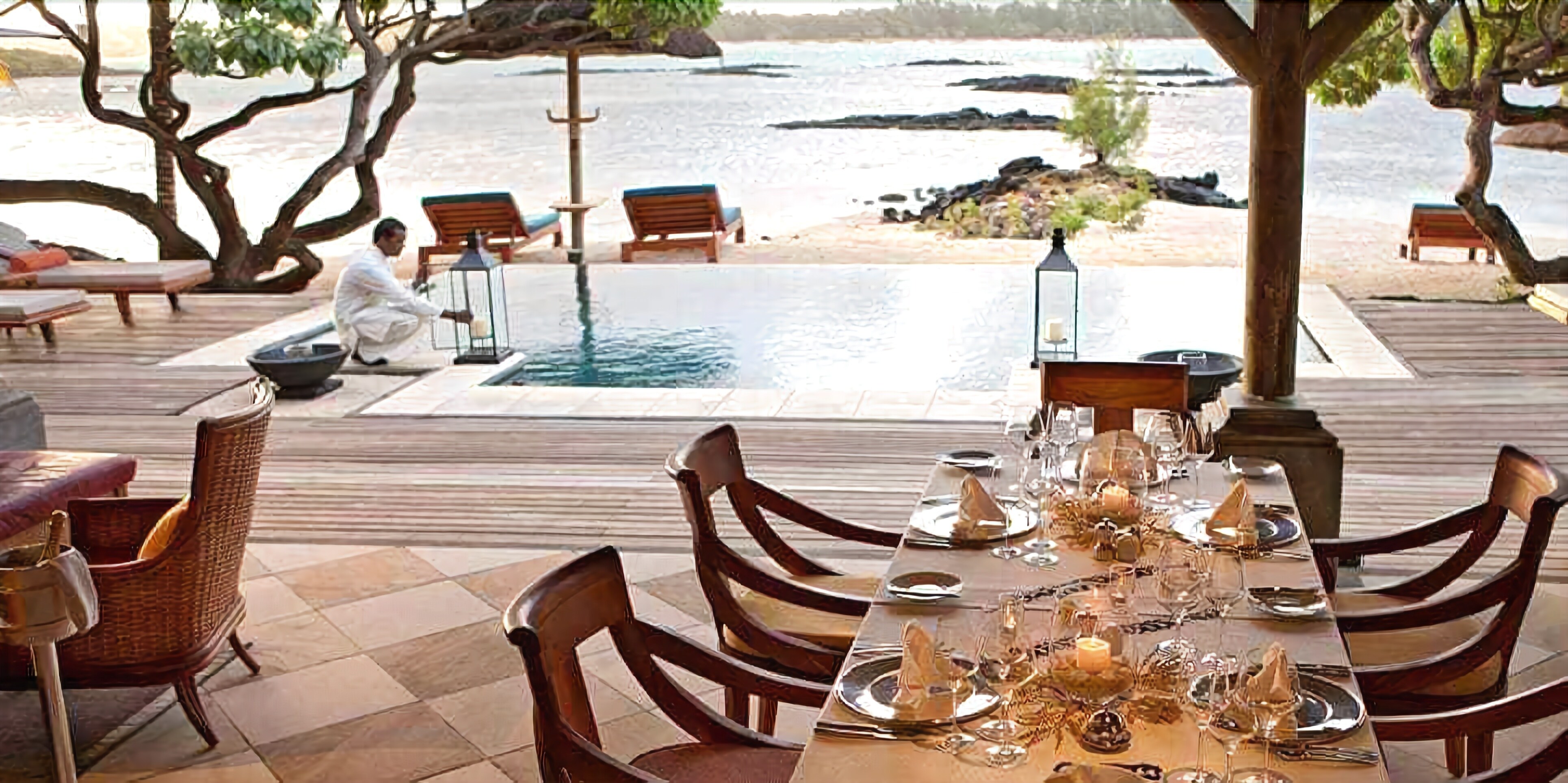 A dining area with a view of the sea, wooden furniture, and a table set for a meal.