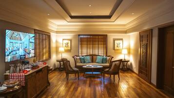 Un hall de hotel con suelo de madera, un conjunto de sofás, un televisor y una estación de café.