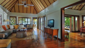 A spacious living area with a wooden ceiling, a television, and a sofa.