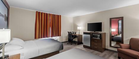 A hotel room with a bed, desk, chair, television, and a microwave.