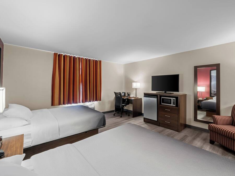 Una habitación de hotel con cama, escritorio, silla, televisor y microondas.