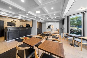 A modern restaurant with a bar area, wooden tables, and chairs.