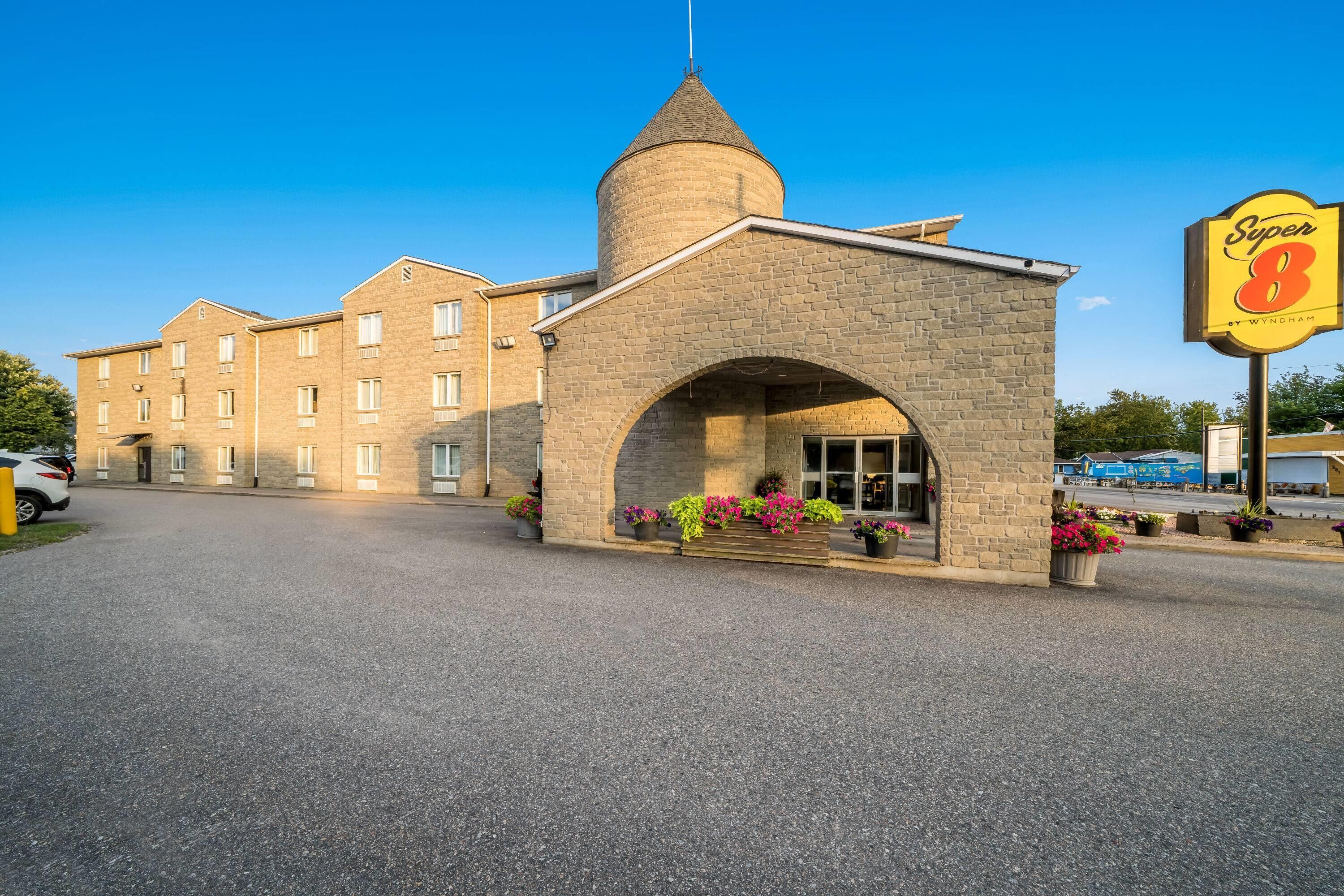 A hotel with a stone tower, a large sign, and a parking lot.