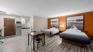 Une chambre d’hôtel équipée d’une kitchenette, de deux lits, d’un bureau et d’une chaise.