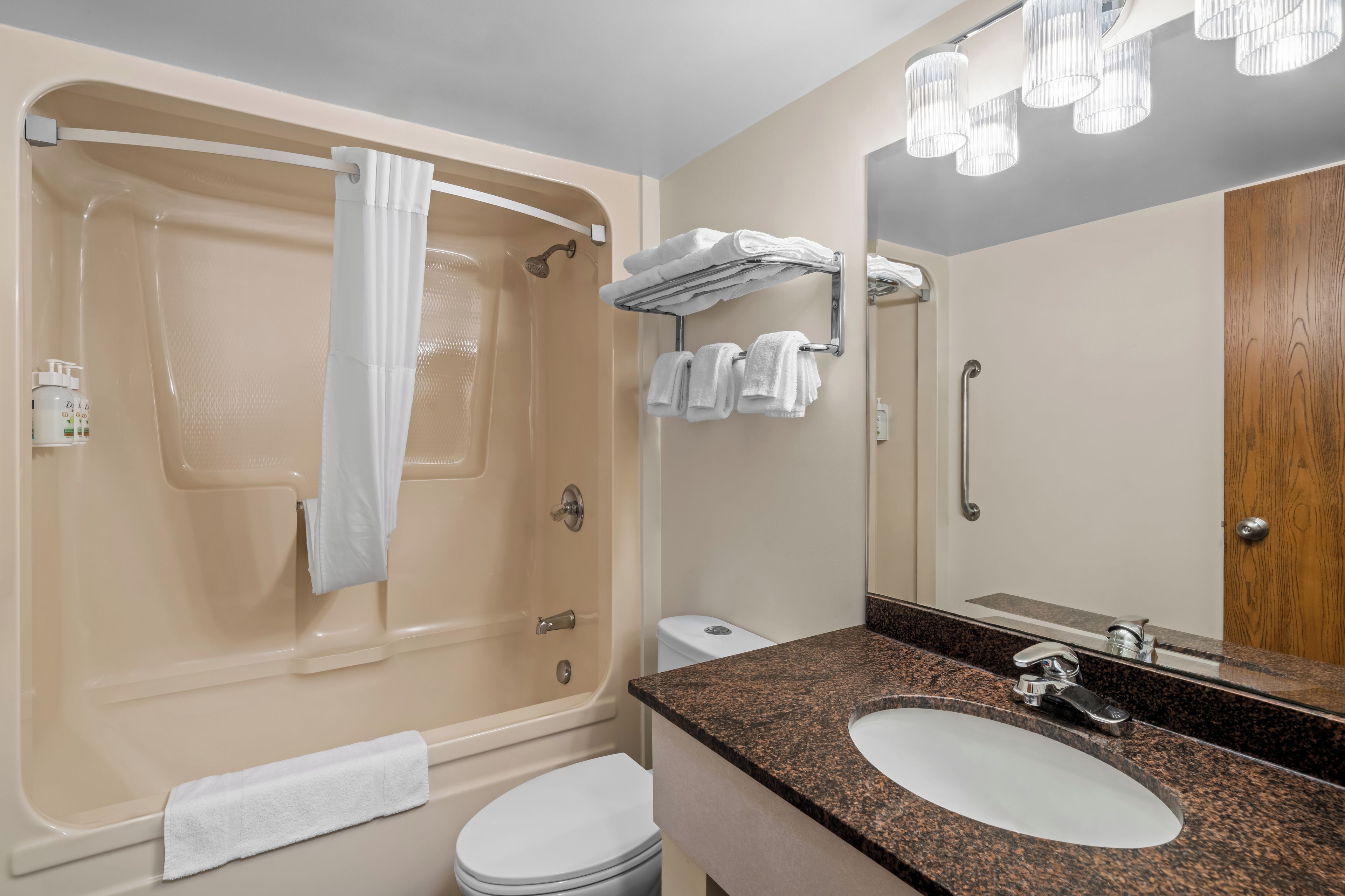 A bathroom with a bathtub, a sink, a toilet, and a mirror.