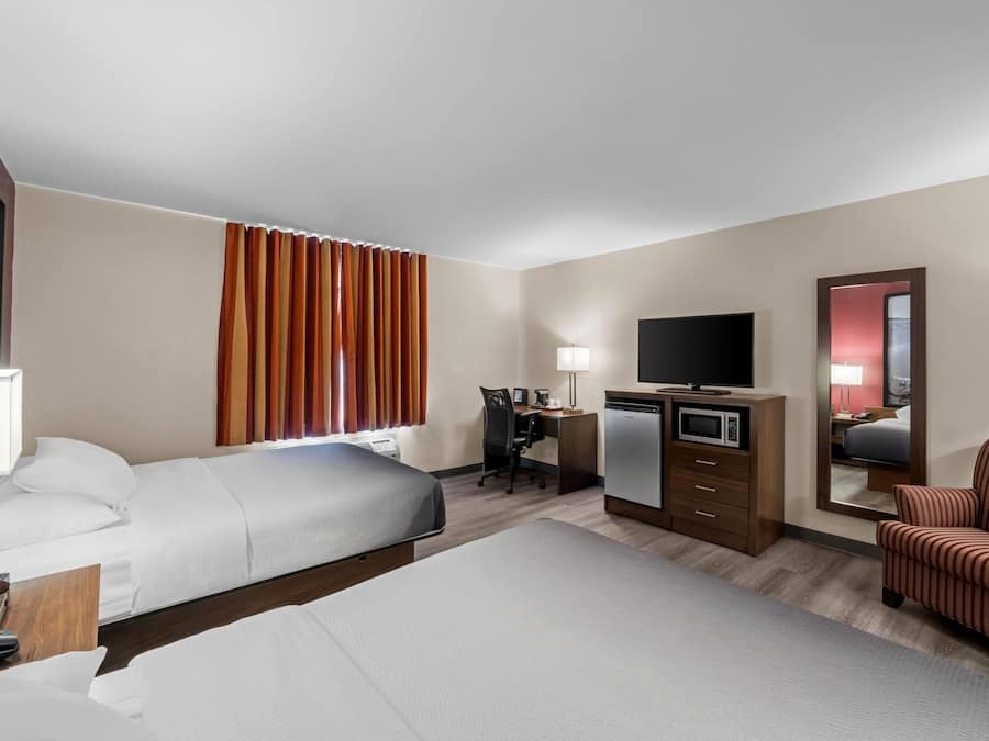 A hotel room with a bed, desk, chair, television, and a mirror.