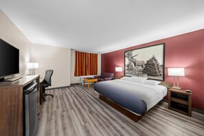 A hotel room with a bed, desk, chair, TV, and a painting on the wall. - Super 8 by Wyndham North Bay (North Bay)