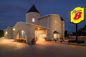 Un hotel con fachada de piedra, una torre central y un letrero que dice 'Super 8 by Wyndham'.