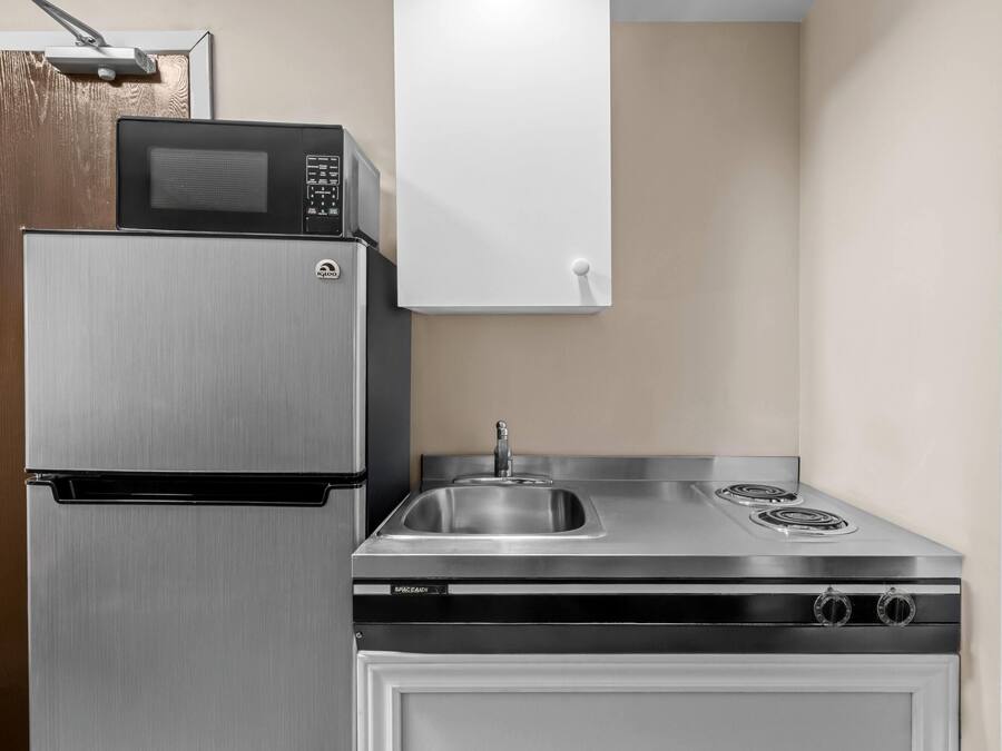 Una cocina compacta con un refrigerador de acero inoxidable, un microondas y una estufa con un lavamanos.