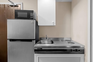 Una cocina compacta con un refrigerador de acero inoxidable, un microondas y una estufa con un lavamanos.
