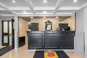 Un área de recepción con un mostrador negro, un logotipo arriba y una puerta a la izquierda.