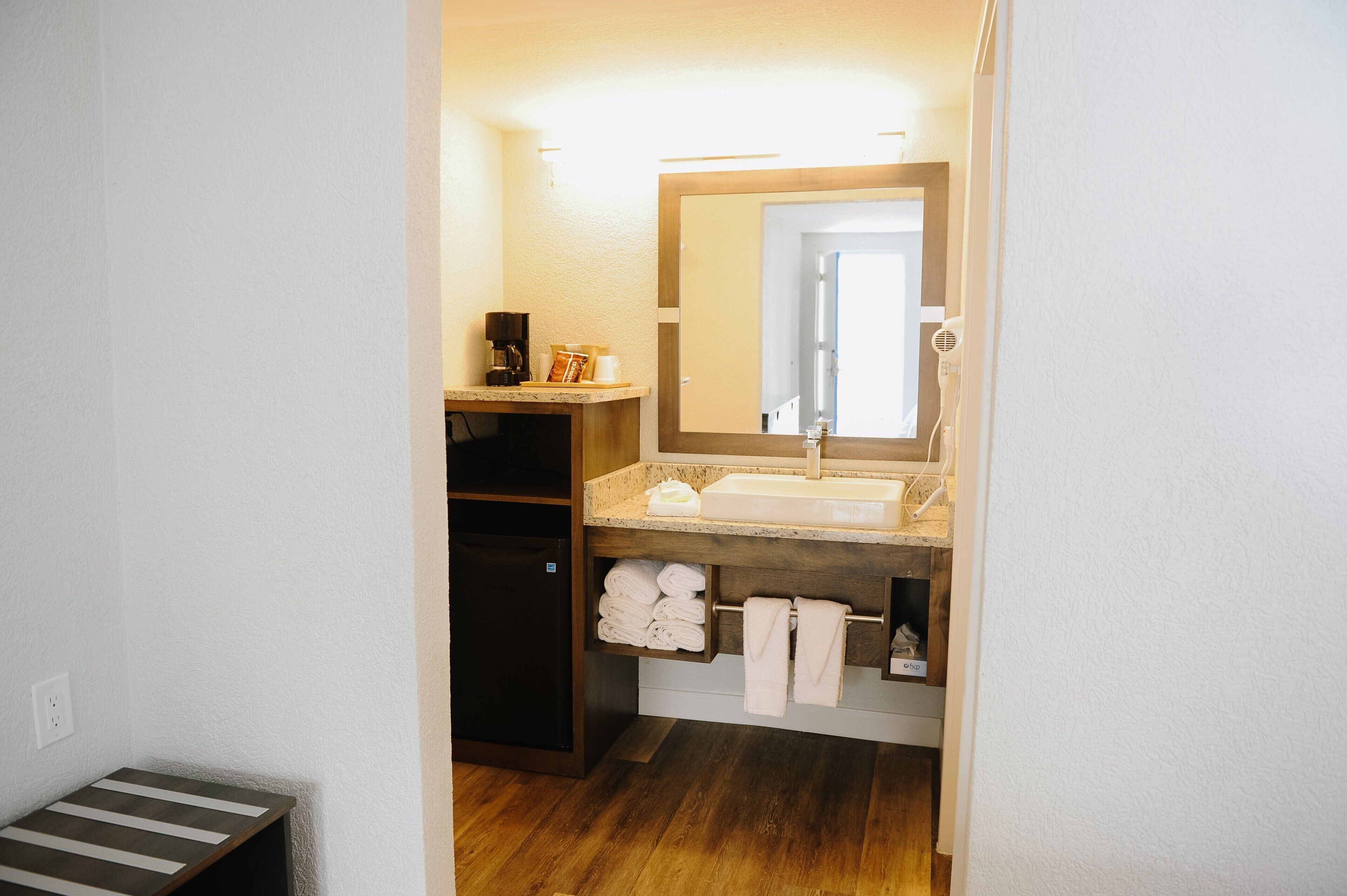 A bathroom with a sink, mirror, towel rack, and a coffee maker.