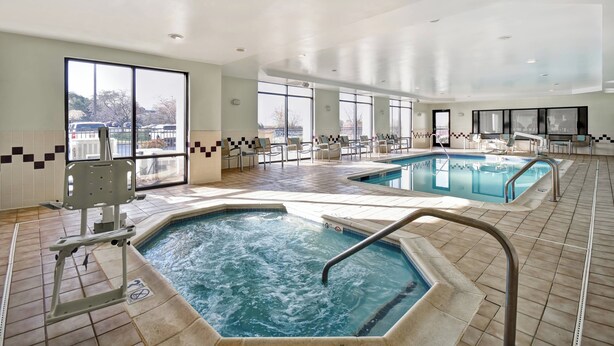 A hotel pool area with two hot tubs and a standard pool, surrounded by chairs and a view of the parking lot. - SpringHill Suites by Marriott Baltimore BWI Airport (Linthicum Heights)