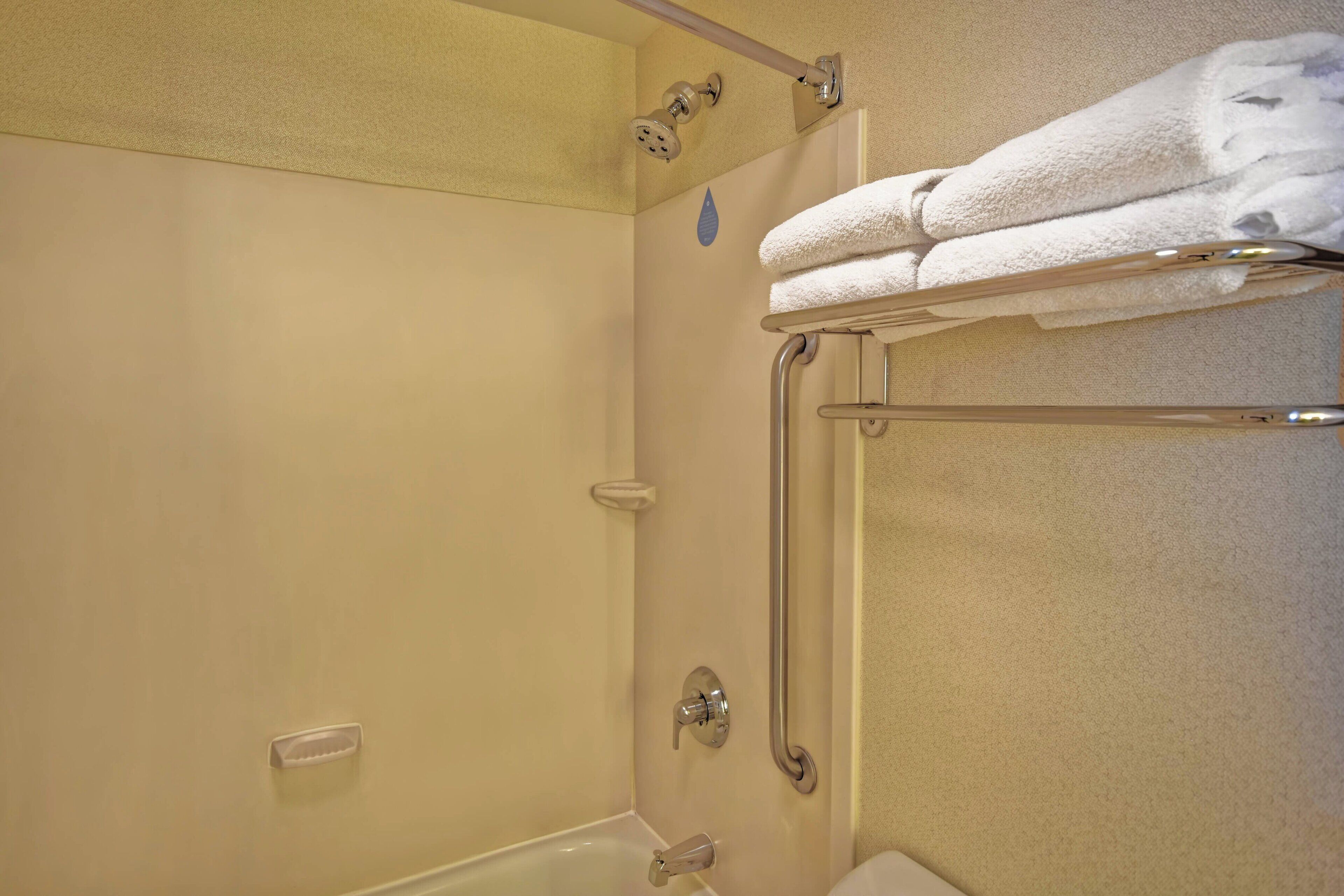 A bathroom with a shower, grab bars, and a towel rack.