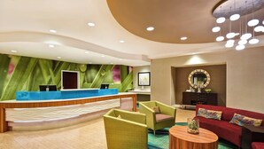A modern reception area with a curved desk, green and red seating, and a patterned carpet. - SpringHill Suites by Marriott Baltimore BWI Airport (Linthicum Heights)