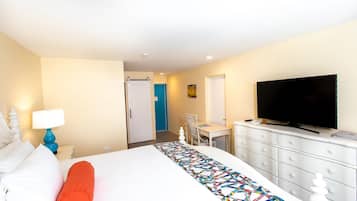 A hotel room with a bed, a desk, a television, and a dresser.