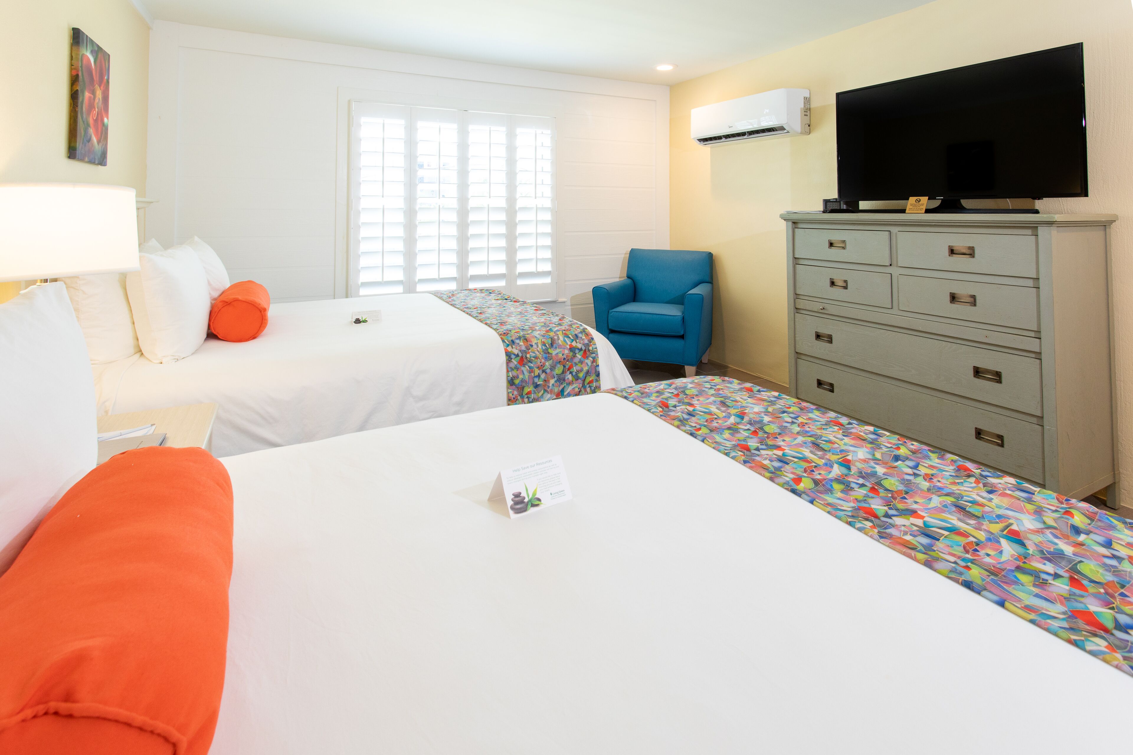 A hotel room with two beds, a TV, a dresser, and a chair.