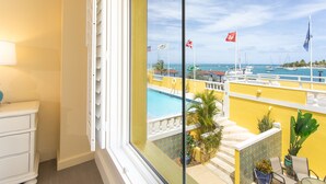 Un balcón con vistas a un puerto deportivo, una piscina y una escalera que lleva a una terraza.
