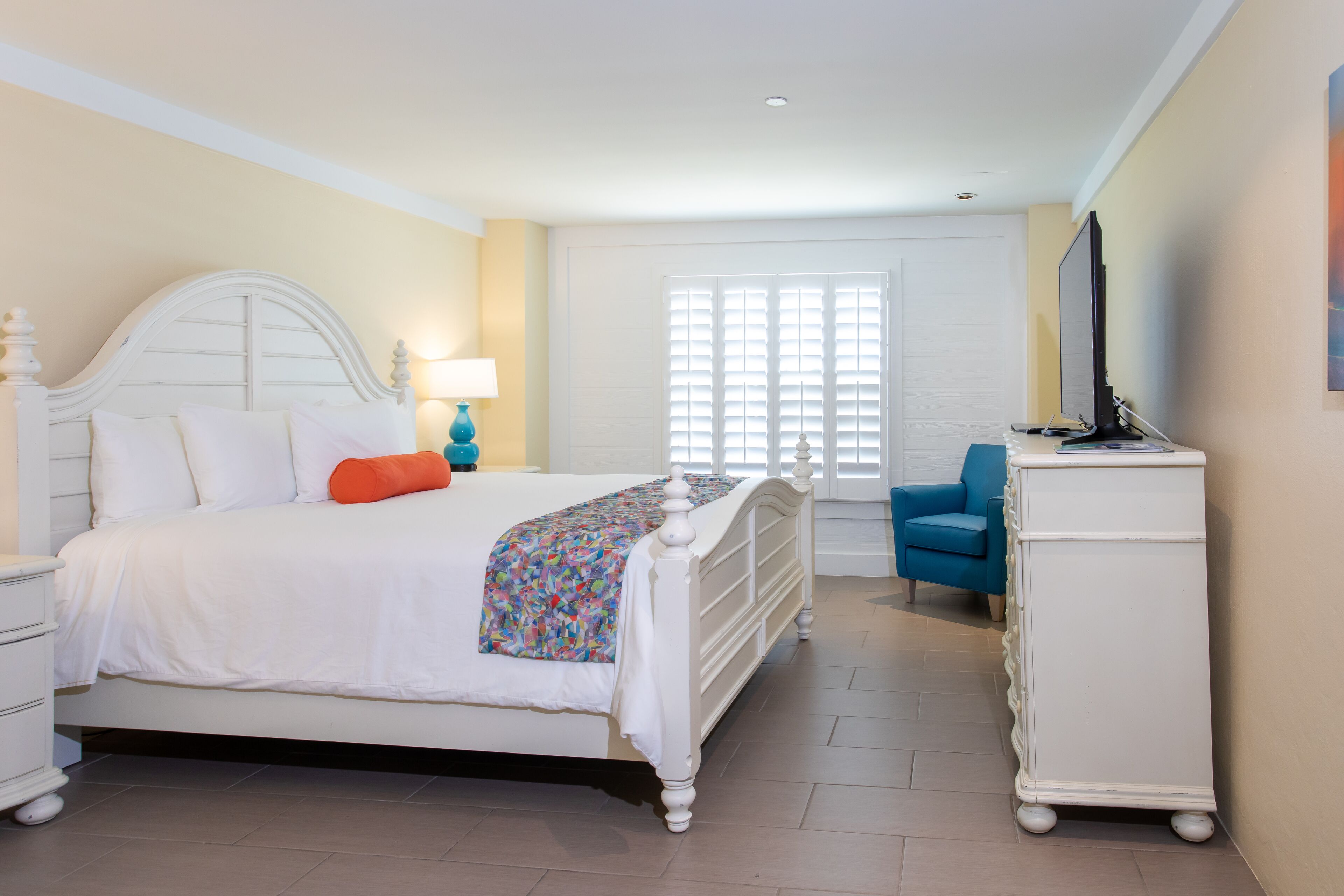A bedroom with a bed, nightstand, dresser, and a chair.