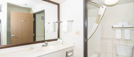 Une salle de bain d’hôtel avec un grand miroir, un lavabo, des toilettes et une douche.