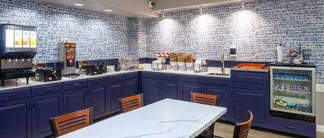 A kitchen with blue cabinets, a marble countertop, and a refrigerator with a beverage dispenser.