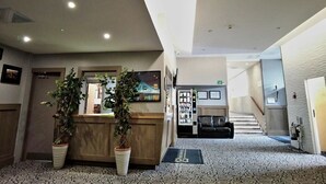 A hotel lobby with a reception desk, a staircase, and a vending machine. - Kings Park Hotel (Glasgow)