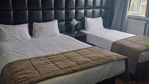 A hotel room with two beds, a dark headboard, white bedding, a bedside lamp, and a window with curtains. - Kings Park Hotel (Glasgow)