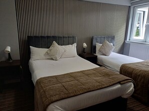 A hotel room with two beds, a striped wall, and a window with blinds. - Kings Park Hotel (Glasgow)