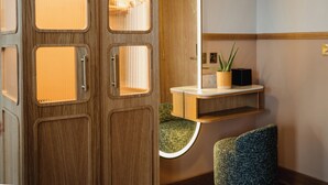 A wooden door with a mirror, a small shelf with a plant, and a green upholstered chair. - Carlton George Hotel (Glasgow)