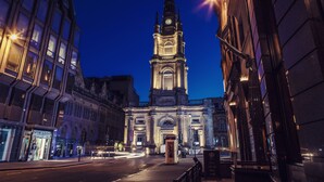 A historic building with a clock tower, a prominent entrance, and a street in front. - Carlton George Hotel (Glasgow)