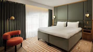 A hotel room with a large bed, a chair, a desk, and a lamp.