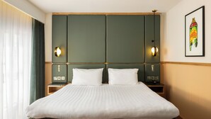 A hotel room with a large bed, two bedside tables, a headboard with wall sconces, and a framed picture on the wall. - Carlton George Hotel (Glasgow)