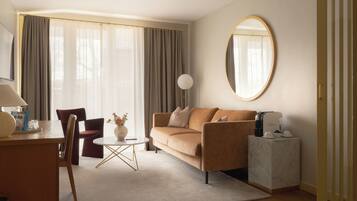 A modern living room with a sofa, a coffee machine, a round mirror, and a dining area with a table and chairs.