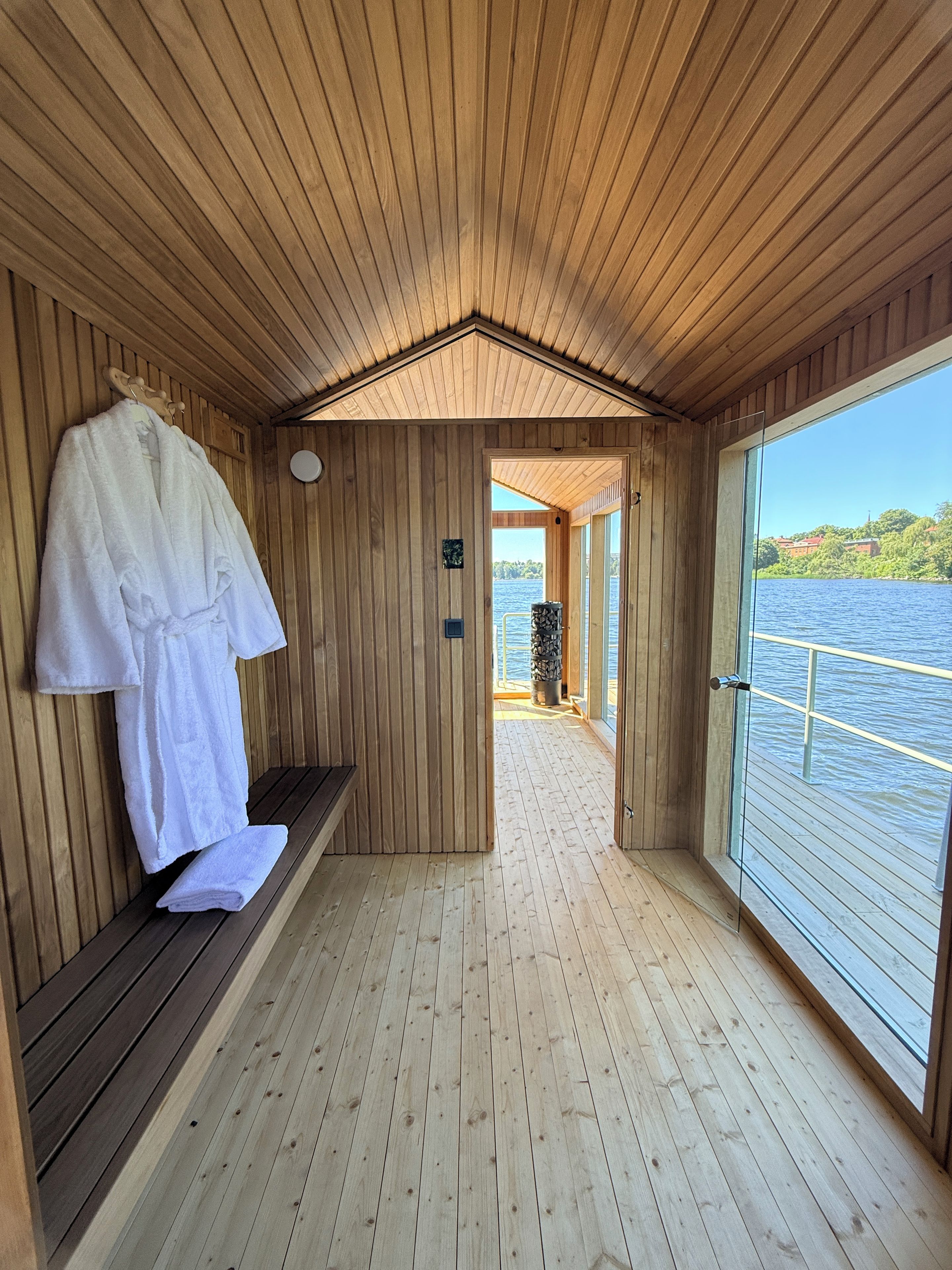 Una cabaña de madera con un banco, un perchero y vistas a un lago.