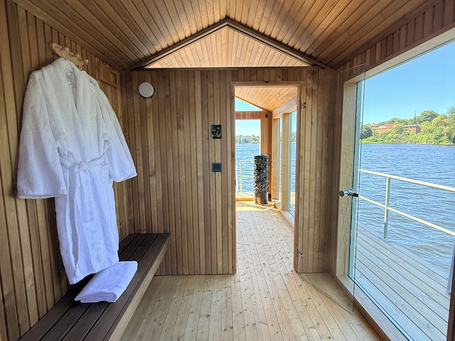Una cabana de fusta amb una banca, un suport per tovalloles i vistes a un llac.
