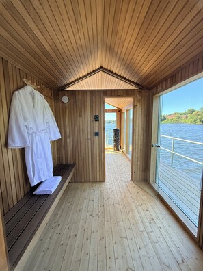 Una cabaña de madera con un banco, un perchero y vistas a un lago.