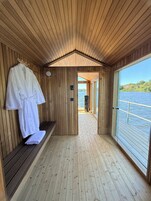 Una cabaña de madera con un banco, un perchero y vistas a un lago.