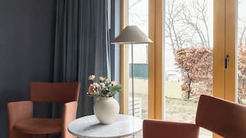 Una habitación moderna con dos sillas rosas, una mesa redonda, un florero con flores y una lámpara de pie.