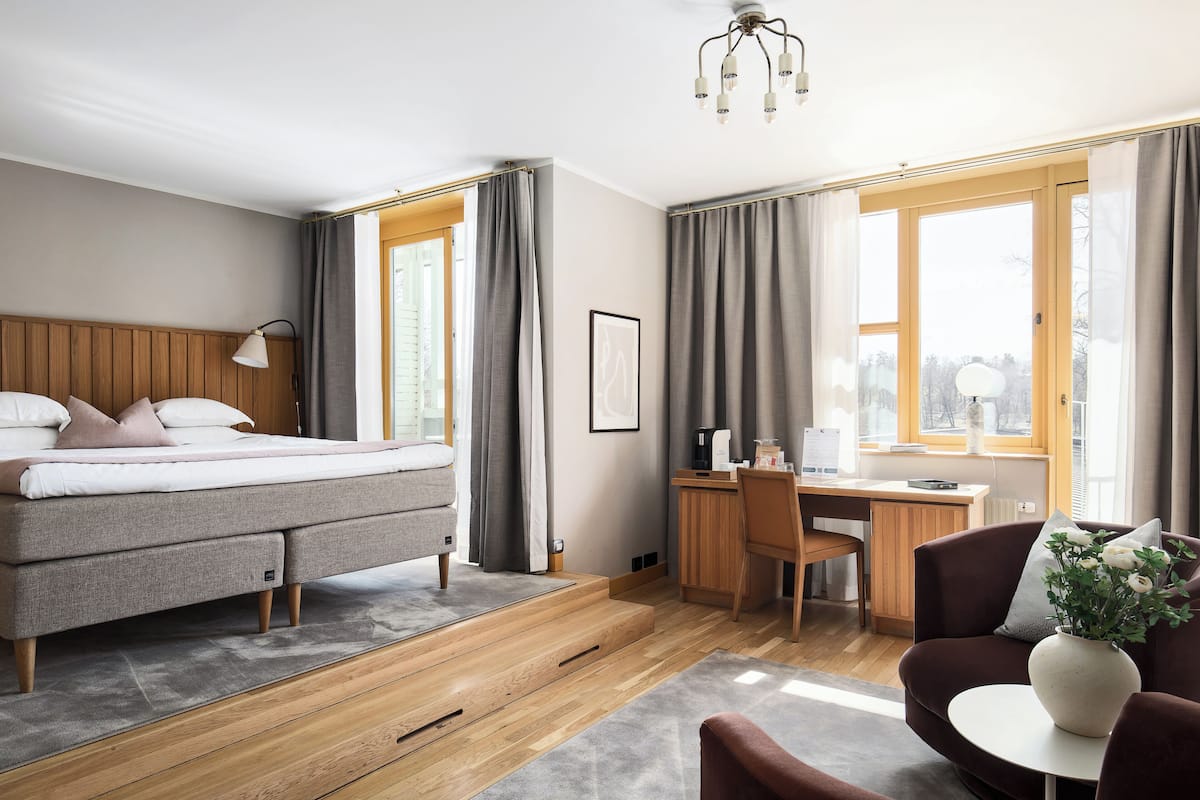 A modern hotel room with a bed, desk, and seating area.