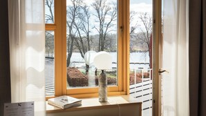 Una habitación con un ventanal grande, una lámpara y un libro sobre una mesa.