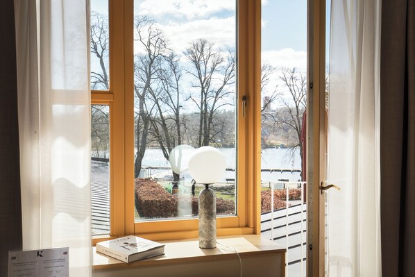 A room with a large window, a lamp, and a book on a table. - Villa Källhagen (Stockholm)