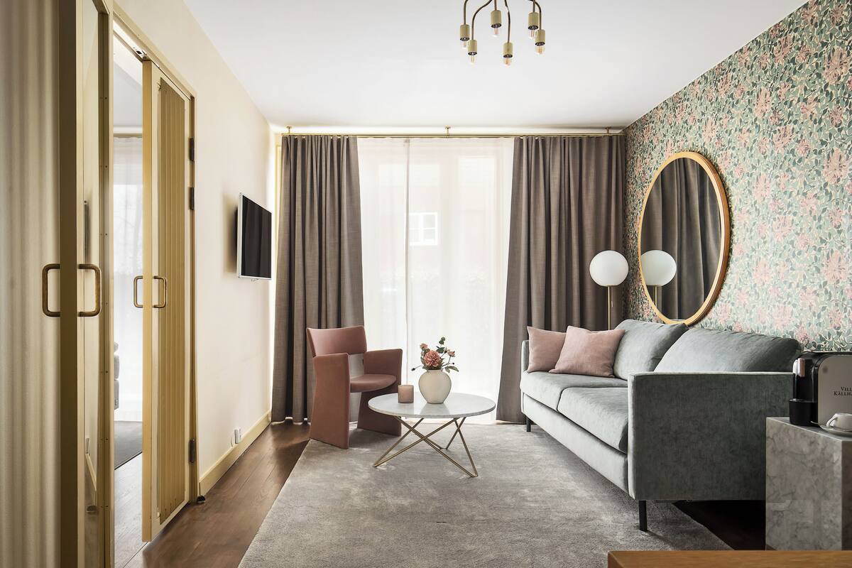A modern living room with a sofa, armchair, coffee table, and a decorative mirror.