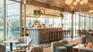 Un área de bar moderna con taburetes, una barra y vistas al exterior.