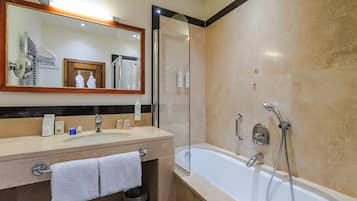 A bathroom with a large mirror, a sink with toiletries, a bathtub, and a shower.