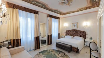Una habitación de hotel con una cama grande, una zona de estar, un espejo y un candelabro.