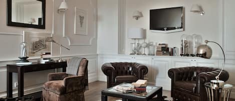 A living room with a fireplace, leather armchairs, a coffee table, and a television.