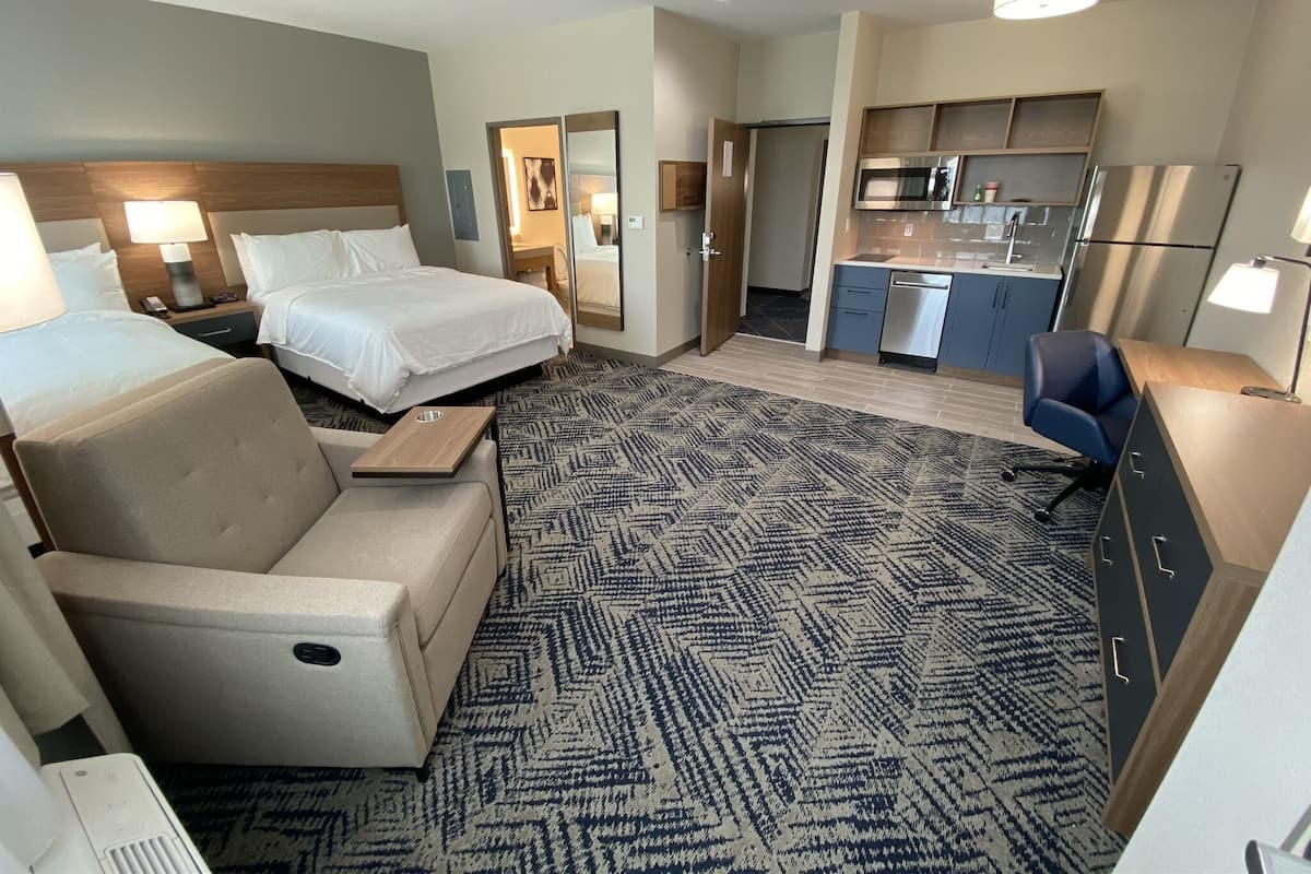 Une chambre d’hôtel comprenant un lit, un canapé, un bureau, une kitchenette et une salle de bain.
