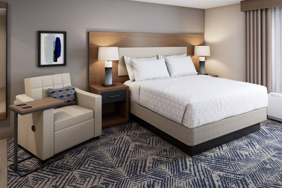 Une chambre d’hôtel avec un lit, des tables de chevet, une chaise et un tapis.