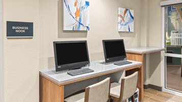 A business nook with two desks, each with a computer and keyboard, and two chairs. There are abstract paintings on the wall and a sign that reads "BUSINESS NOOK".