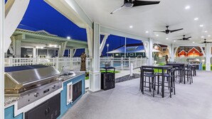 Un patio exterior con una parrilla, zona de estar y ventiladores de techo.